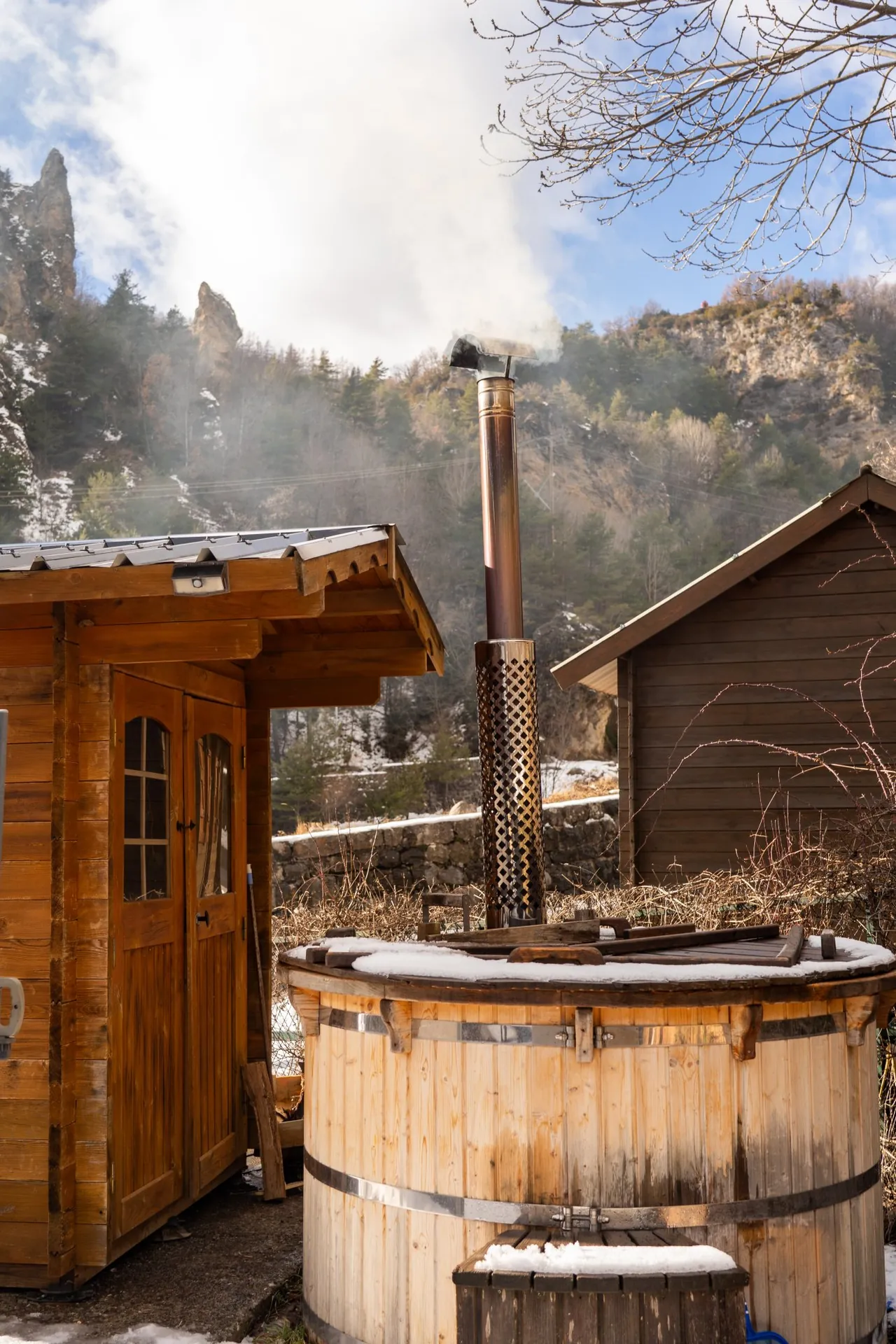 Bain nordique en bois et cabane, face à la montagne